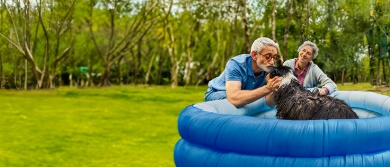 Elderly couple playing with their dog outdoors